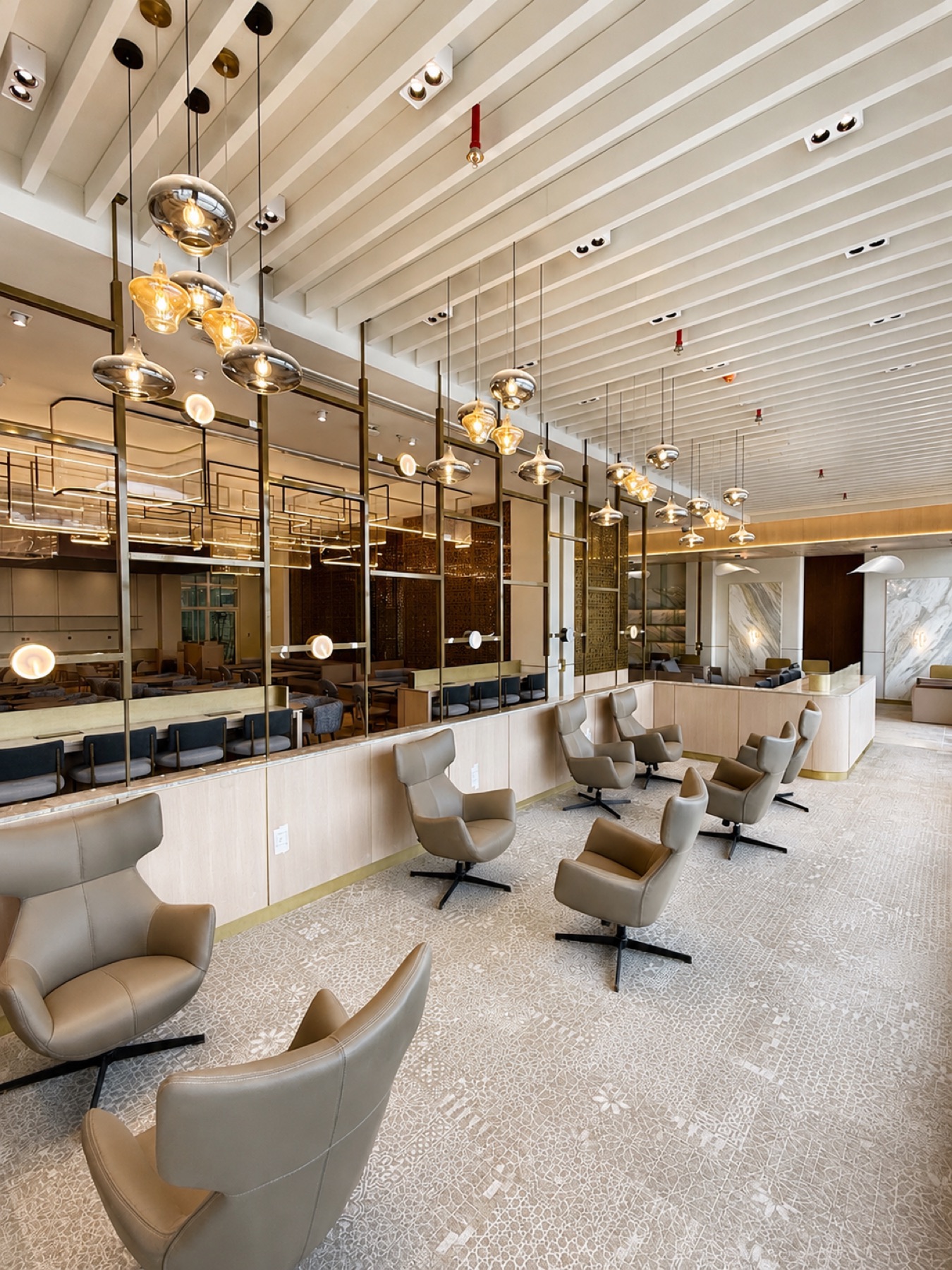 Wingback lounge chairs beneath amber glass pendants