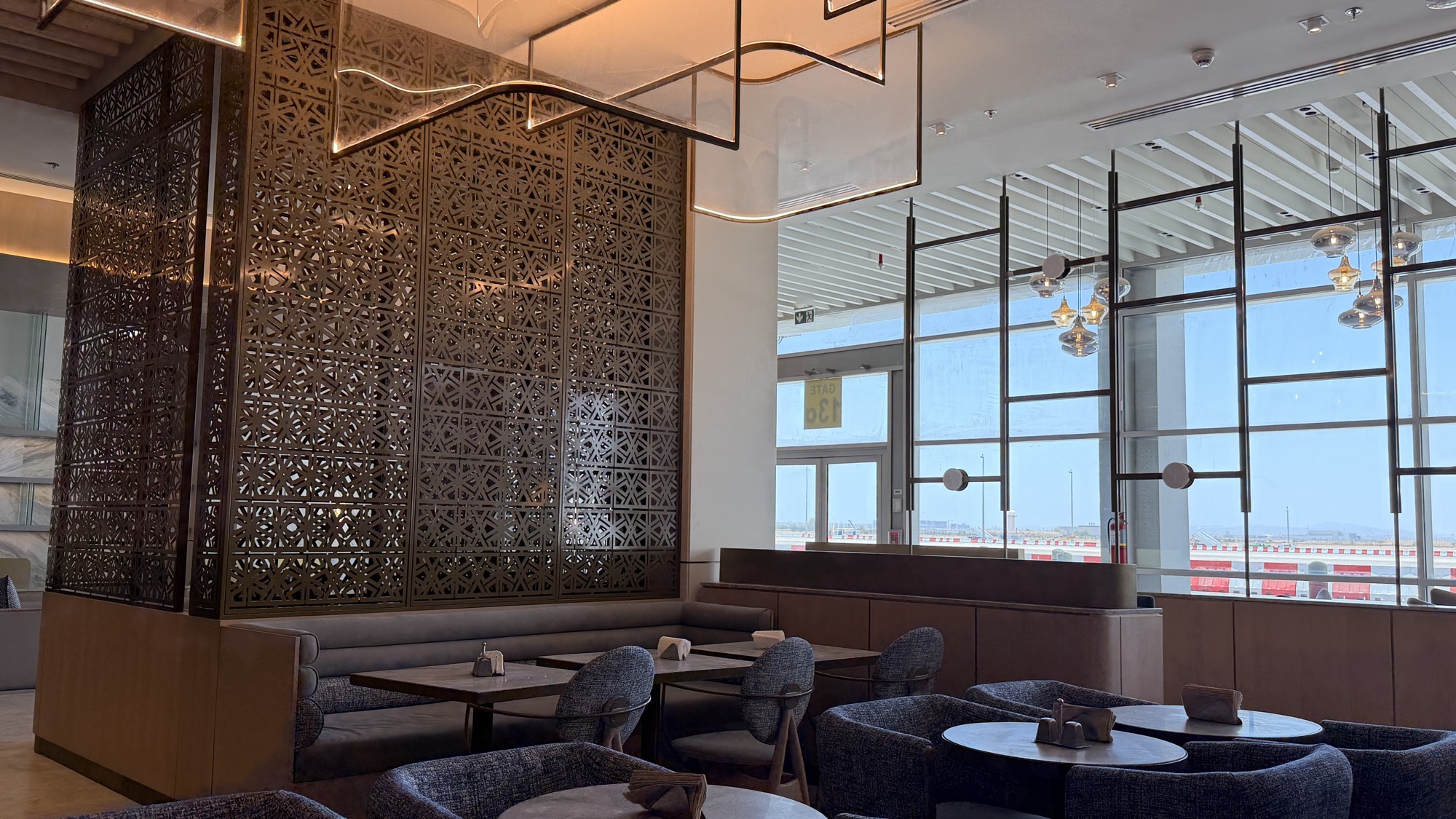 Safa Lounge interior with brass mashrabiya screens and runway views